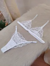 Conjunto de lencería compuesto por un bralette de encaje con breteles regulables y una tanga regulable con corte media less, confeccionado con encaje floral y detalle de entrepierna de algodón.