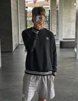Buzo negro de corte clásico con cuello redondo, puños y ruedo acanalados con doble línea blanca. Logo de Umbro bordado en el pecho. Mangas con paneles laterales en gris. Confeccionado en algodón y poliéster.