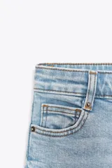 Jeans de tiro alto y corte ancho (wide leg) hasta el tobillo, confeccionados en denim azul de efecto lavado. Presenta cinco bolsillos y cierre frontal con cremallera y botón.