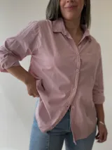 Camisa celeste de corte holgado, con cuello clásico, cierre frontal con botones, bolsillo en el pecho y mangas largas con puños abotonados.