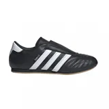 Championes Adidas modelo Taekwondo, color negro con las tres tiras características en blanco y suela de goma color caramelo. Presentan un diseño minimalista sin cordones, con costuras acolchadas en la puntera y detalle de marca en el talón.