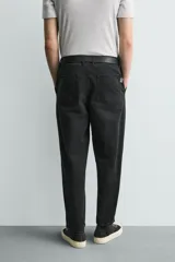 Pantalón de corte carrot fit confeccionado en tejido de algodón con estructura diagonal y efecto lavado. Presenta bolsillos frontales con bolsillo cerillero, bolsillos traseros de plastrón y cierre frontal con cremallera y botón.