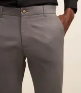 Pantalón slim color tostado, confeccionado en sarga, con cierre de botón y cremallera, y bolsillos tipo cuchillo.