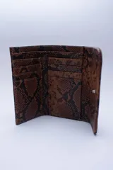 Billetera negra de cuero con textura tipo cocodrilo, con múltiples ranuras para tarjetas y billetes.