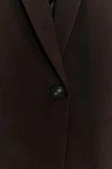 Blazer de cuello solapa y manga larga, con bolsillos delanteros con solapa y cierre frontal de un botón. Presenta un diseño estructurado con forro interior.