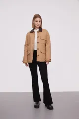 Campera color beige con cuello marrón de cuero sintético, cierre con botones a presión, cuatro bolsillos frontales y puños con botón.