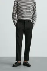Pantalón chino de corte slim fit, confeccionado en tejido elástico. Presenta bolsillos frontales, bolsillos traseros de vivo con botón y cierre frontal con cremallera y botón.