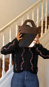 Bolso tipo matera confeccionado en cuero vacuno, con diseño estructurado y manija superior integrada. Presenta un cuerpo con franjas diagonales en gamuza de colores contrastantes (amarillo, verde y azul) sobre una base de cuero marrón, con detalles de costuras artesanales en los bordes.