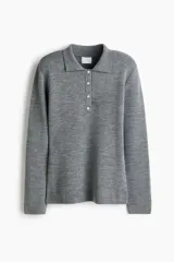 Buzo de punto suave color gris, con cuello clásico estilo polo, tapeta con botones frontales, mangas largas y hombreras.