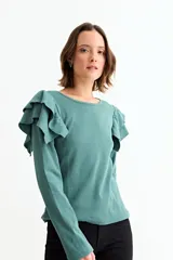 Remera de manga larga en tejido acanalado, color verde, con detalle de volados en los hombros y cuello redondo.