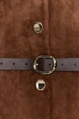 Blazer de cuello redondo y manga larga, confeccionado en tejido efecto ante. Presenta cierre frontal con botones, bolsillos con tapeta en el pecho y cinturón ajustable en la cintura.