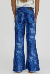 Pantalón de jean con estampado batik en tonos azules y blancos, corte acampanado y ruedo desflecado.