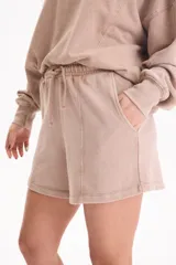 Short de felpa sin frisa con efecto acid wash color tostado, bolsillos laterales, tiro medio-alto, cintura elástica con cordón ajustable y costuras decorativas delanteras.