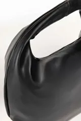 Bolso negro tipo hobo de cuero sintético, con asa corta fija y cierre superior.