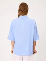 Camisa de manga corta celeste, confeccionada en mezcla de algodón y lino, con cuello camisero y cierre frontal de botones.