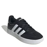 Championes urbanos Adidas modelo Urban Barreda T, con diseño inspirado en siluetas retro de los 80. Presentan una capellada que combina cuero sintético y gamuza en color negro, con las icónicas tres tiras laterales en blanco y suela de goma blanca.