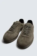 Zapatilla de estilo urbano confeccionada en piel con acabado de serraje en color marrón. Presenta cierre mediante cordones al tono, detalle de pespuntes en el empeine y suela de goma a tono.