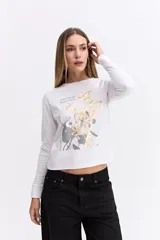 Remera de manga larga color gris oscuro, con cuello redondo y estampa gráfica frontal en tonos blancos y celestes con motivos florales y texto.