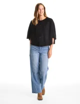 Capa de tejido de punto con diseño de doble capa superpuesta, cuello a la base y cierre frontal con botones. Presenta mangas estilo japonés con terminaciones acanaladas y una silueta holgada con movimiento fluido.