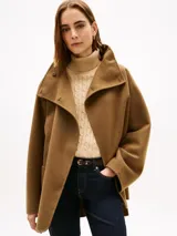 Abrigo de corte oversize confeccionado en mezcla de lana de doble cara, color marrón. Presenta cuello chimenea, cierre frontal con un botón visible y otro oculto, y dos bolsillos delanteros de parche.