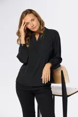 Blusa de manga larga con escote en V y diseño de doble capa frontal. Presenta puños abotonados y una caída fluida.