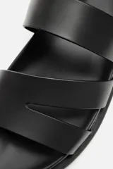 Sandalias negras con tiras anchas, ajuste con hebilla y plantilla anatómica. Suela plana a tono.