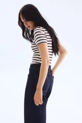 Pantalón de jean azul oscuro, de tiro alto, corte ancho y largo tobillero. Presenta bolsillos delanteros con botón y bolsillos traseros abiertos.