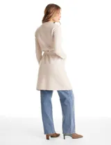 Chaqueta de punto color beige con frente abierto, cuello con solapa, mangas largas y bolsillos frontales. Incluye un lazo para ajustar en la cintura.