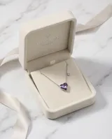 Collar de plata con cadena fina y dije en forma de corazón de cristal violeta tornasolado, acompañado de un pequeño detalle de cristal brillante en la cadena.