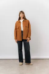 Sobrecamisa de gabardina liviana color crema, con corte oversize, cuello clásico, cierre frontal con botones a presión y dos bolsillos delanteros con solapa.