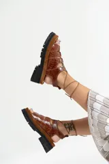 Sandalias de cuero color marrón con textura de cocodrilo, plataforma con suela track y tiras finas que se atan al tobillo.