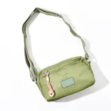 Bandolera verde con correa larga regulable, cierre superior y bolsillo frontal con cierre.