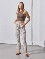 Pantalón de lino color beige con rayas verticales grises, corte recto, cintura alta con cordón ajustable y bolsillos laterales.