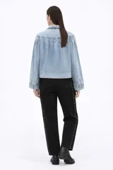 Campera de jean en tono celeste claro, con diseño de frunces en la parte superior delantera, mangas largas con puños ajustados y cierre frontal mediante botones metálicos.