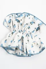 Gomita para el pelo de diseño voluminoso, con estampado floral en tonos celestes sobre fondo blanco y terminación de ruloté celeste en los bordes.