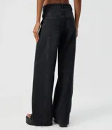 Pantalón wide leg de denim negro, con cintura media, bolsillos funcionales, presillas para cinturón y cierre frontal con botón y cremallera.