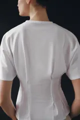 Camiseta de algodón con cuello redondo y manga corta. Presenta un diseño entallado con pinzas en la cintura y bajo recto.