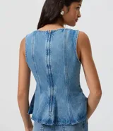 Blusa sin mangas confeccionada en jean de algodón, con escote redondo, corte entallado y diseño peplum con dobladillo evasé y recortes estructurados.