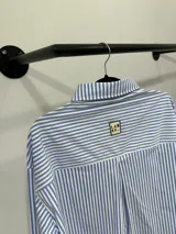 Camisa celeste con rayas verticales blancas, de corte holgado y mangas largas.