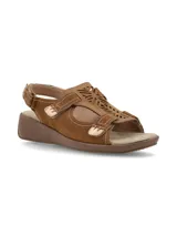 Sandalias Hush Puppies modelo Juliana Tan, de cuero color marrón tostado con detalles de perforaciones láser en el empeine, costuras visibles y cierre con tiras autoadheribles. Cuenta con suela de goma con plataforma baja tipo cuña.
