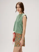 Short de cintura alta y calce holgado, con estampado geométrico en tonos verdes, naranjas y celestes, con cordón ajustable rojo en la parte frontal.