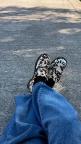 Mocasín de cuero con pelo vacuno en estampado animal print, diseño artesanal y suela firme.