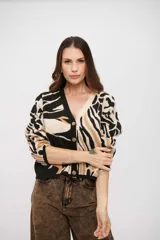Saco tejido de punto con diseño animal print abstracto en tonos negro, beige y tostado. Presenta escote en V, cierre frontal con botones y mangas largas con puños ajustados.