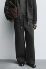Pantalón de corte wide fit confeccionado en tejido técnico con efecto neopreno. Presenta cintura elástica ajustable con cordón, perneras anchas con costura frontal, bolsillos laterales y bolsillos traseros de plastrón.