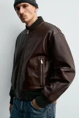 Cazadora bomber de corte regular confeccionada en piel encerada color marrón oscuro. Presenta cuello, puños y bajo en tejido rib elástico, cierre frontal con cremallera y bolsillos laterales con cierre.