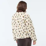 Chaqueta de sherpa color crema con estampado floral en tonos marrones, amarillos y verdes. Tiene cuello camisero y ribete de pana marrón.