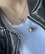 Collar plateado con dije esférico texturizado con incrustaciones de gemas de colores.