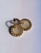 Aros colgantes dorados con dije circular de resina color turquesa, bordeado con strass. El arito es de acero quirúrgico.