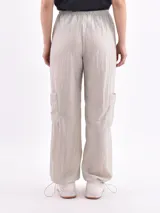 Pantalón marrón de corte ancho, con cintura elástica ajustable con cordón, bolsillos laterales y bolsillos tipo cargo en los muslos.