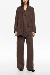 Chaqueta de corte cruzado color marrón, con cuello de solapa, cierre mediante lazo en la cintura y bolsillos de plastrón frontales.